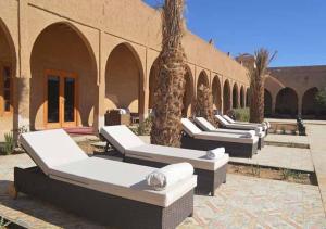 a row of beds sitting outside of a building at Kasr Tin Hinane in Merzouga