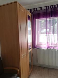 a room with a cabinet and a window with purple curtains at Ferienwohnungen Frank in Cochem