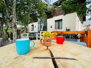 uma mesa de madeira com duas chávenas e um vaso com flores em Ioska's House em Mestia