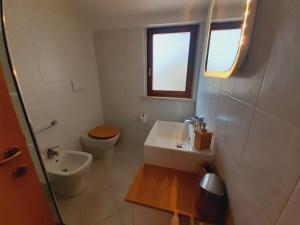 uma casa de banho com um lavatório, um WC e uma janela. em Villetta Gelsomino ,150 metri dal mare, ingresso indipendente, posto auto e giardino, marina di grosseto em Marina di Grosseto