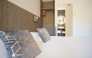 a bedroom with a bed with a pillow and a mirror at The Originals City, Hôtel Le Lodge, Bayonne Nord in Ondres