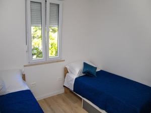 a bedroom with two beds and two windows at Apartment Matea in Mokošica