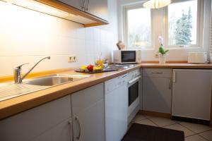 a white kitchen with a sink and a microwave at Ferienwohnungen an den Salzwiesen in Boltenhagen