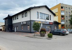 a building with a car parked in a parking lot at Pokoje Noclegi Brzozowski in Wysokie Mazowieckie