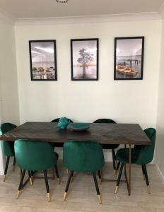 tavolo da pranzo con sedie verdi e quadri alle pareti di Pet friendly home with pool and boat parking. a Iluka