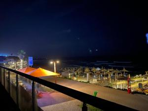 - une vue sur une plage de nuit avec des parasols dans l'établissement Luxery stay with seaview, pool, green space & Sunset orientation near Rabat, à Sidi Bouqnadel