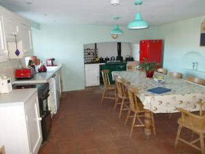 uma cozinha com uma mesa com cadeiras e um frigorífico vermelho em Farmer Bob's Farmhouse em Barnstaple