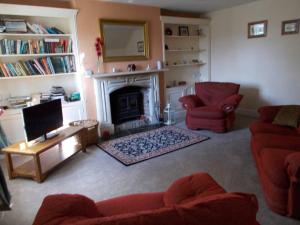 a living room with red furniture and a fireplace at Farmer Bob's Farmhouse in Barnstaple