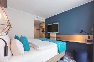a hotel room with a bed and a tv at Holiday Inn - the niu, Yen Hamburg City by IHG in Hamburg