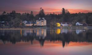 a house on the shore of a lake at sunset at Screebe House in Rosmuck