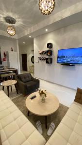 a living room with a couch and a tv on a wall at WASAN LUXURY RESIDENCE HAWANA Salalah in Salalah