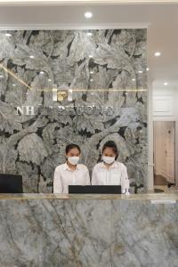 順化的住宿－Nhật Phương Hotel，两名妇女戴面具在电脑前