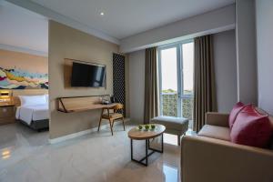 a hotel room with a couch and a bed at favehotel Pamanukan in Pamanukan-hilir