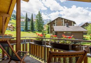 a balcony with two chairs and flowers on it at Chalet Stella Duplex Penthouse in Wengen