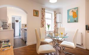 cocina y comedor con mesa de cristal y sillas en Bright 3 bedroom townhouse near city centre en Norwich