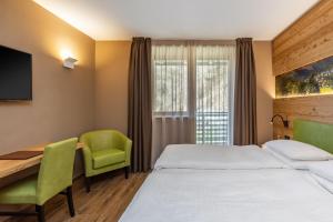 Pokój hotelowy z łóżkiem i biurkiem w obiekcie Hotel Vittoria - Ricarica l'anima w mieście Dimaro