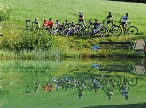 a group of people riding bikes next to a pond at Ski in Ski out Hotel Unterellmau in Saalbach-Hinterglemm