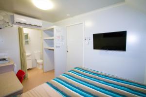 um quarto com uma cama e uma televisão na parede em Meekatharra Accommodation Centre em Meekatharra