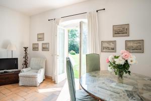 ein Wohnzimmer mit einem Glastisch mit einer Blumenvase in der Unterkunft Bright APT surrounded by greenery with parking & Shared Pool in Villa Guardia