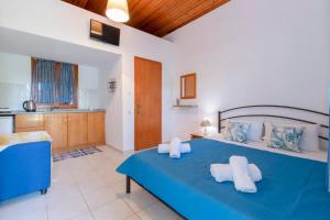 a bedroom with a blue bed and a kitchen at melissi studios in Paralia Sikias