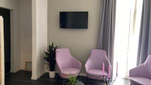 a room with two pink chairs and a tv at Hotel Delle Camelie in Florence