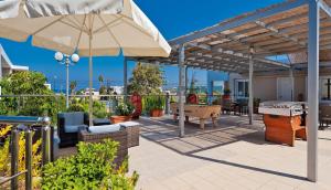 a patio with an umbrella and tables and chairs at Hotel Koukouras in Stalos