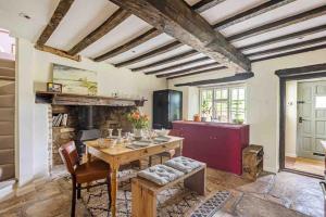 a living room with a table and a fireplace at Cotswold Stone Cottage in Poulton
