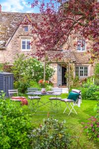a garden with chairs and a table in front of a house at Cotswold Stone Cottage in Poulton