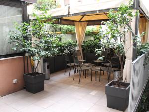 eine Terrasse mit Topfpflanzen sowie einem Tisch und Stühlen in der Unterkunft Hotel Soperga in Mailand