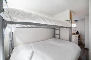 een slaapkamer met 2 stapelbedden met witte lakens bij Room in Studio - Mini Studio Peniche au coeur de Lyon, insolite et calme in Lyon