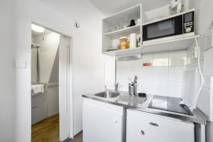 a white kitchen with a sink and a microwave at Room in Studio - Mini Studio Peniche au coeur de Lyon, insolite et calme in Lyon