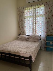 sypialnia z łóżkiem i oknem z zasłonami w obiekcie Magnolia 1 Homestay w mieście Kuala Besut