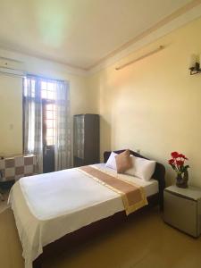 a bedroom with a bed with white sheets and a window at Bao Minh Hotel in Hue