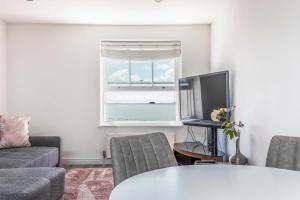 sala de estar con sofá, TV y ventana en Ashbys Seafront 2 Bedroom Apartment en Portsmouth