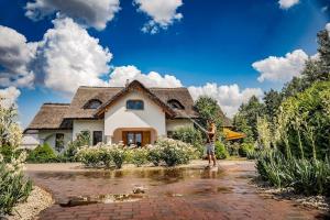 une femme est debout sur un tuyau devant une maison dans l'établissement Csoda Szarvas Birtok, à Szarvas