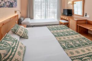 Habitación de hotel con 2 camas y TV en GHT Oasis Tossa & Spa, en Tossa de Mar