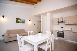 Una cocina y una sala de estar con una mesa y sillas blancas. en Dimora Mascagni - Goelba, en Portoferraio