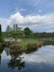 a pond with a gazebo next to a fence at Camping De La Sarre in Abreschviller