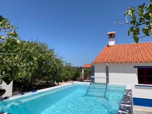 a swimming pool in front of a house at Quinta Samor in Aljezur