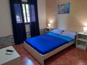 a bedroom with a bed with blue sheets and blue pillows at La Cycas in Trabia