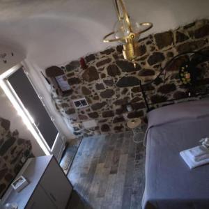 1 dormitorio con ventilador de techo y pared de piedra en La Cantinetta di Sve, en Riccò del Golfo di Spezia