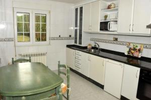 a kitchen with white cabinets and a green table at LA BUGANVILLA in Gijón
