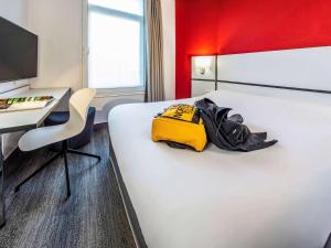 une chambre d'hôtel avec un lit avec un sac jaune dans l'établissement Ibis Styles Strasbourg Centre Gare, à Strasbourg
