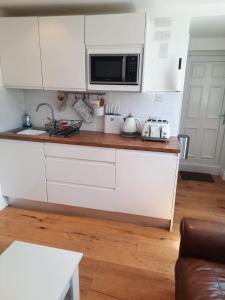 a kitchen with white cabinets and a microwave at Woodside Annexe in Paignton