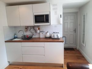 a kitchen with white cabinets and a microwave at Woodside Annexe in Paignton