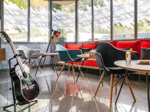 une chambre avec une guitare, des chaises et des tables dans l'établissement IBIS Cannes Mouans Sartoux Piscine parking gratuit, à Mouans-Sartoux