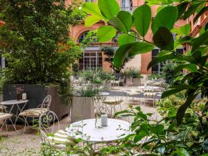 une cour avec des tables et des chaises et un bâtiment dans l'établissement Ibis Styles Toulouse Capitole, à Toulouse
