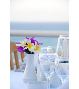 a table with a vase with flowers and wine glasses at Denizkizi Hotel in Kyrenia