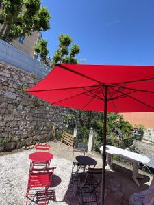 a red umbrella and some chairs and a table and a bench at SOLEIL ZEN in Grasse