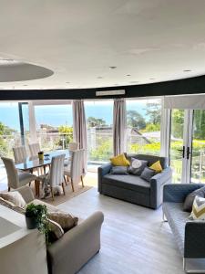 a living room with couches and a table and chairs at One of the best properties in Lyme! Breathtaking views across the whole bay. 3 stories with 2 tier veranda around the property. Sleeps 6 in Lyme Regis